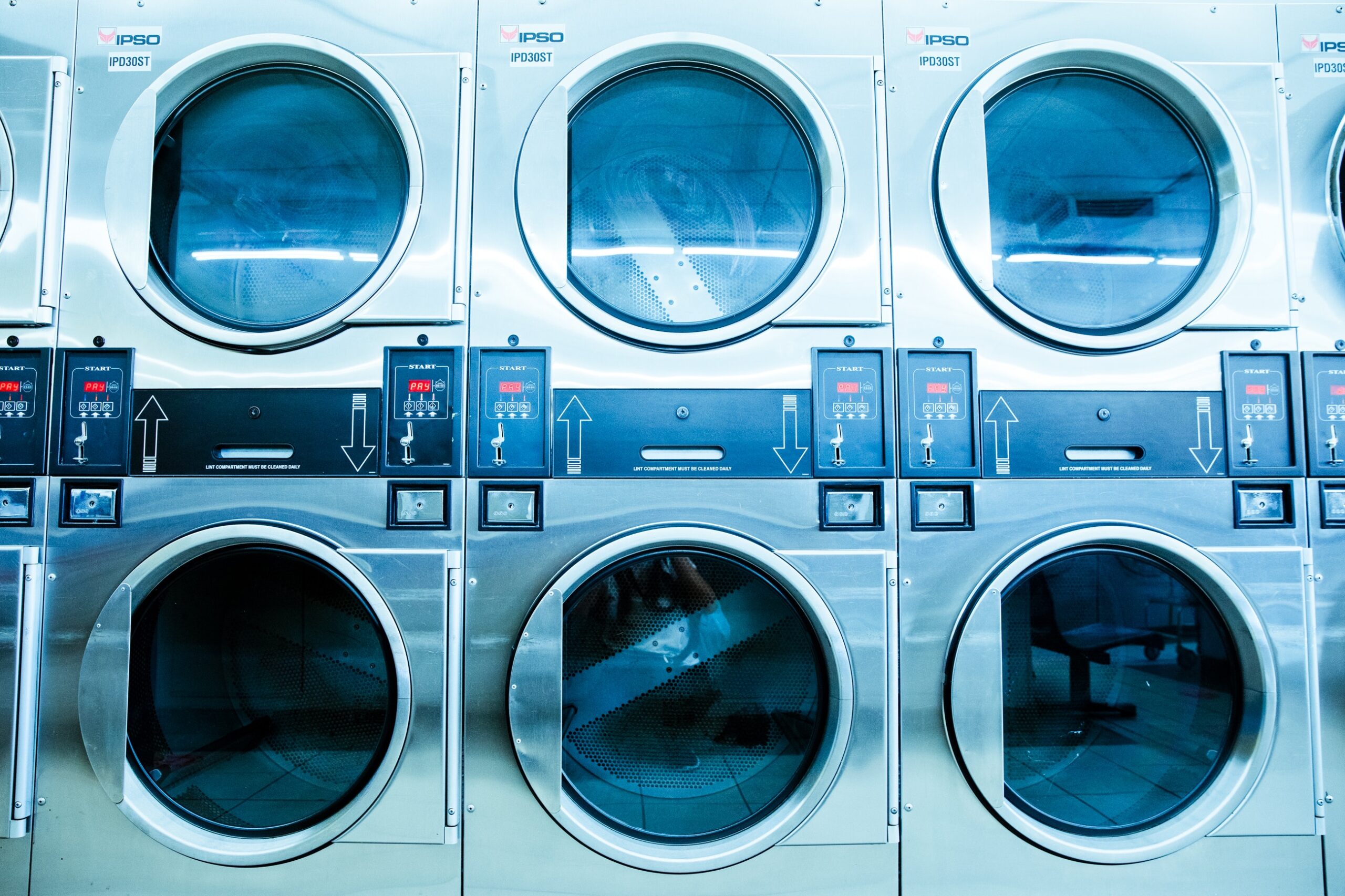 Row of commercial washing machines in laundromat.