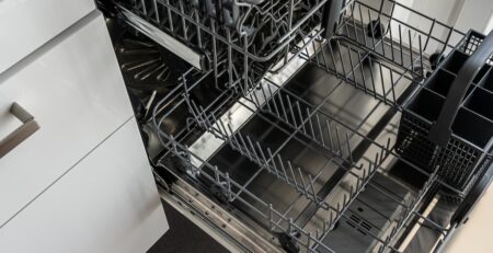 Empty open dishwasher interior with racks.