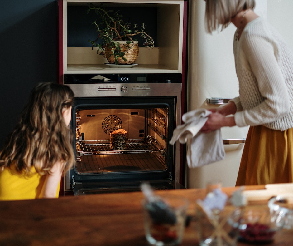 Woman baking, child watching, kitchen setting.